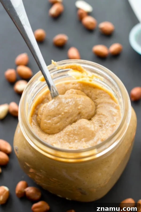 Maple Vanilla Peanut Butter Perfection 5 Ingredients for homemade peanut butter: peanuts, maple syrup, vanilla extract, and cinnamon, arranged on a surface.