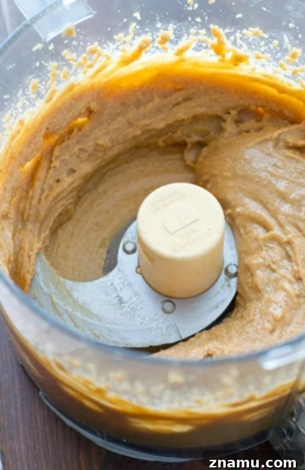 Maple Vanilla Peanut Butter Perfection 6 Close-up of freshly blended, smooth peanut butter inside a food processor.