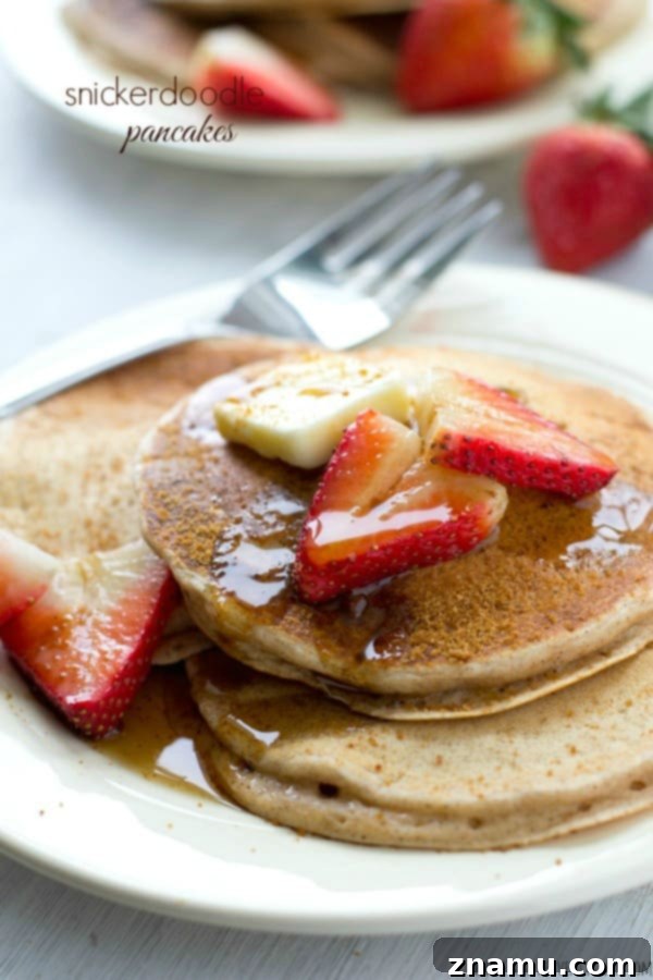 Tall, fluffy snickerdoodle pancakes dusted with cinnamon sugar and drizzled with maple syrup, capturing the taste of the beloved cookie in breakfast form.