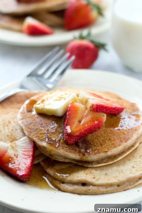 A close-up shot of a stack of snickerdoodle pancakes, highlighting the steam rising, suggesting they are freshly made and wonderfully warm.