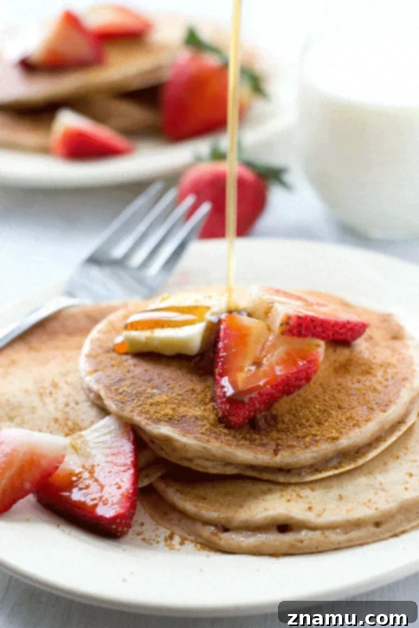 An overhead shot of snickerdoodle pancakes, generously drizzled with maple syrup and sprinkled with extra cinnamon sugar, emphasizing their sweet appeal.
