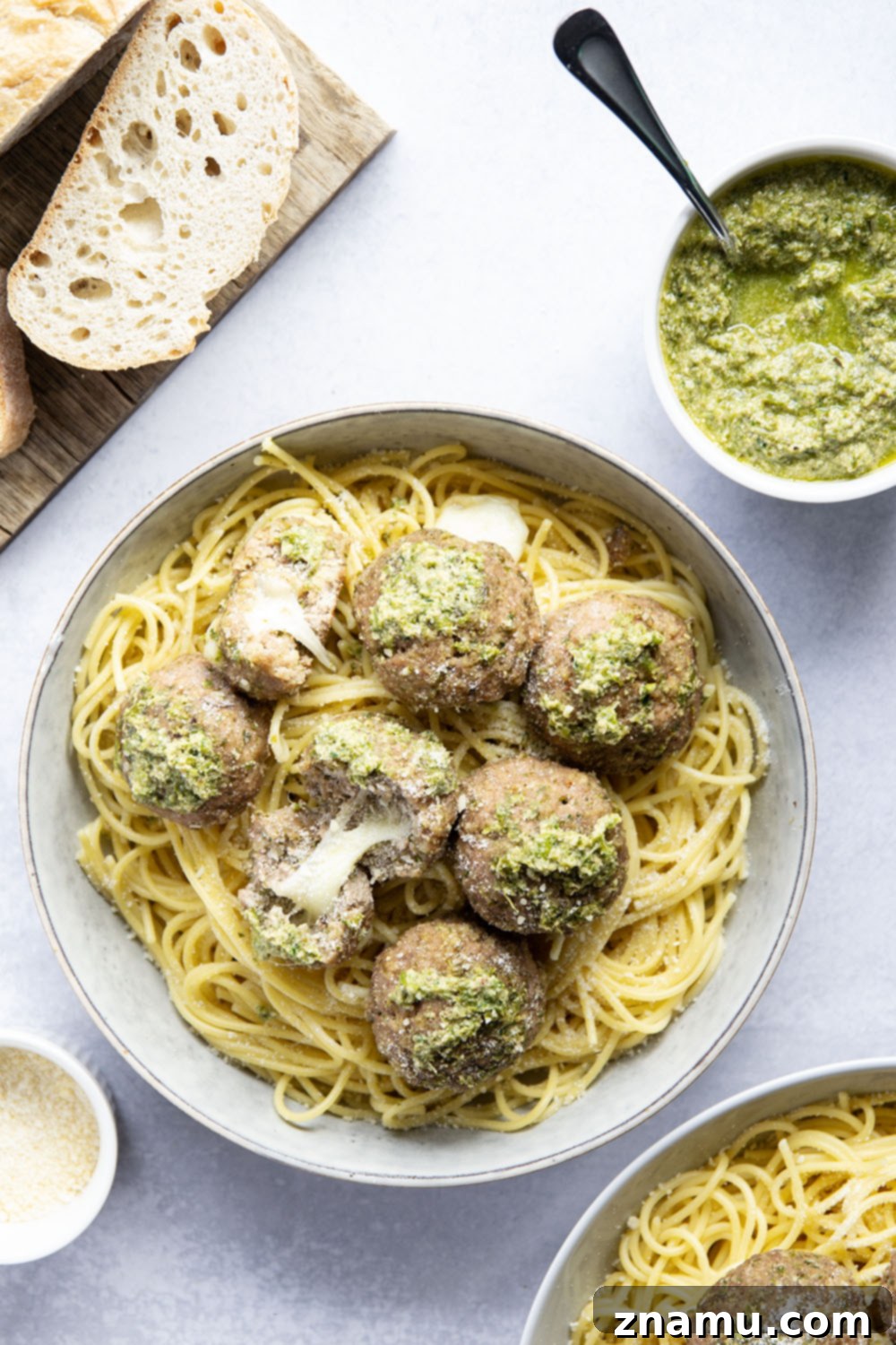 Melted Mozzarella Pesto Turkey Meatballs 3 A serving of mozzarella-stuffed pesto turkey meatballs over spaghetti with parmesan cheese.