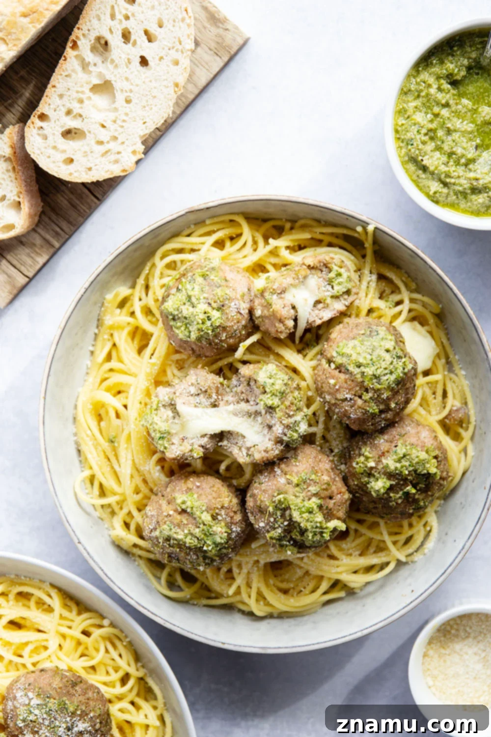 Melted Mozzarella Pesto Turkey Meatballs 6 A close-up of a mozzarella-stuffed pesto turkey meatball with cheese oozing out, on a fork.