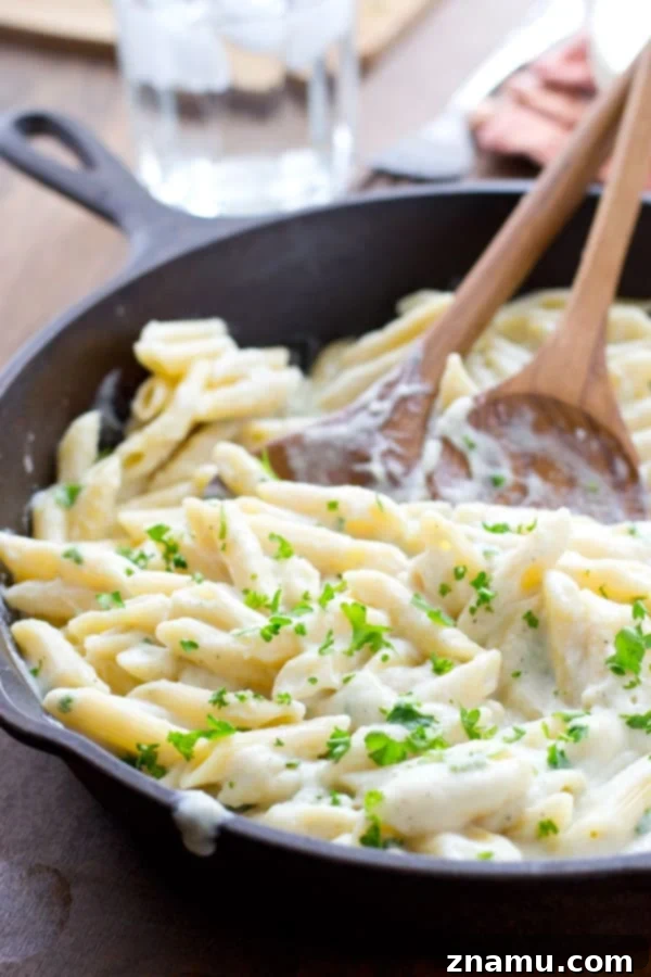 Quick Creamy Cauliflower Pasta Alfredo 3 Cauliflower-based Alfredo sauce being tossed with pasta in a pan, showcasing its rich and creamy texture. @WholeHeavenly