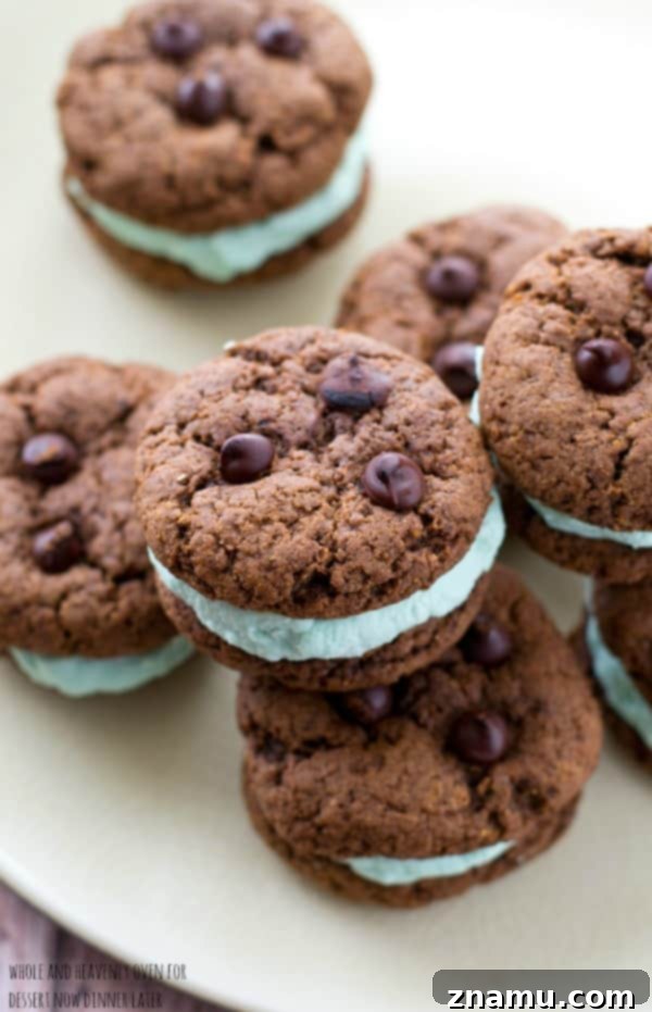 Creamy Chocolate Mint Cookie Sandwiches 4 Hand holding a delicious Double Chocolate Mint Cream Sandwich Cookie, showcasing its vibrant green filling and chewy texture.
