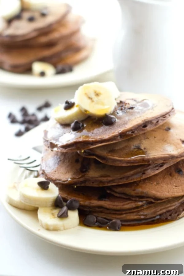 Decadent Double Chocolate Banana Pancakes 5 A generous serving of Double Chocolate Banana Pancakes drizzled with maple syrup, capturing the essence of a comforting and indulgent breakfast.