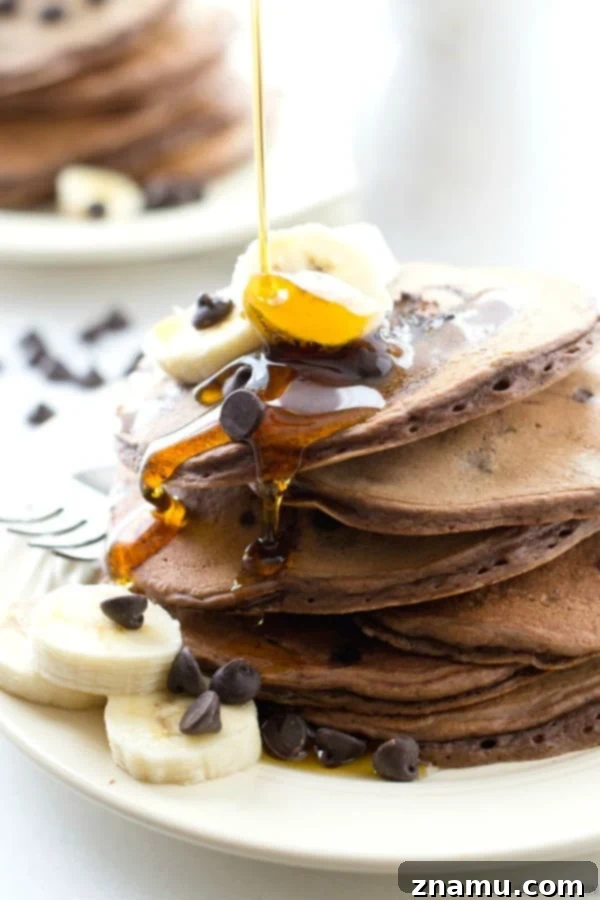 Decadent Double Chocolate Banana Pancakes 7 A visually stunning shot of Double Chocolate Banana Pancakes being generously drenched in maple syrup, highlighting their appeal as a breakfast feast.