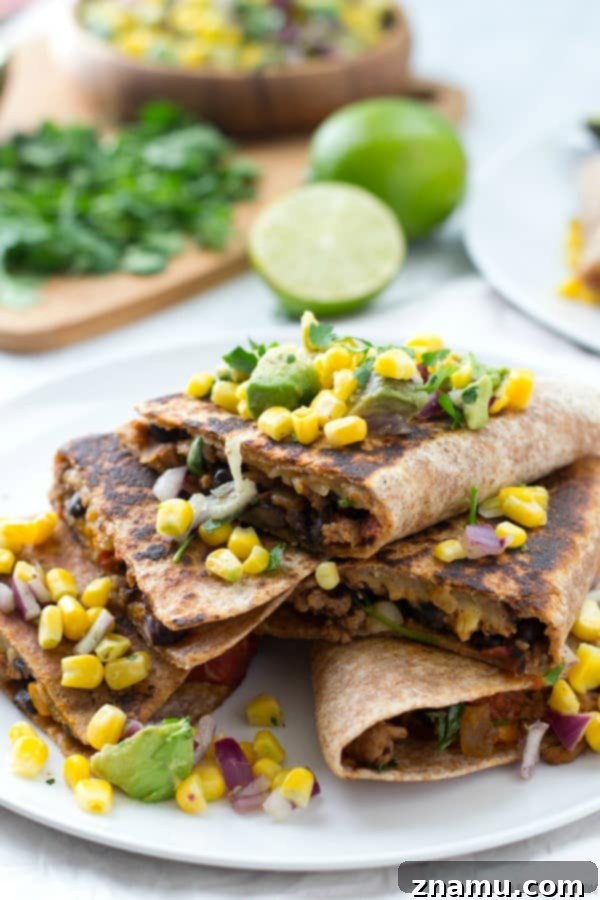 Fully assembled Beef and Bean Quesadillas topped generously with fresh Corn-Avocado Salsa