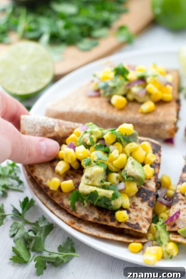 A serving platter with multiple Beef and Bean Quesadillas and a bowl of Corn-Avocado Salsa, ready to be enjoyed