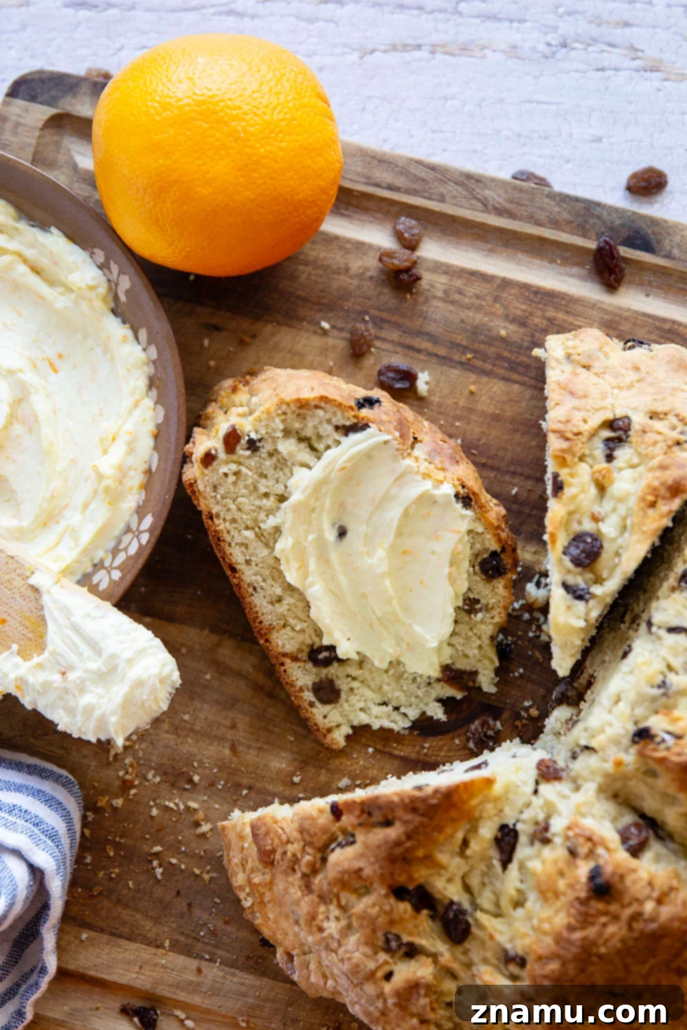 Sunshine Orange Irish Soda Bread with Cream Cheese 6 A perfectly golden-brown Irish soda bread loaf, sliced and presented with a bowl of orange cream cheese.