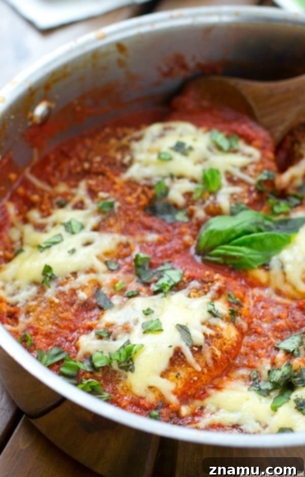 30-Minute One-Pan Chicken Parmesan 7 Delicious one-skillet chicken parmesan plated with hot pasta and a side of fresh basil, ready for a satisfying meal.