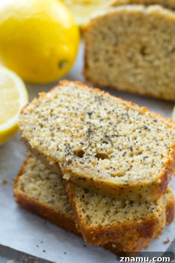 Zesty Poppy Drizzle Loaf 2 Sliced Glazed Lemon Poppy Seed Bread with a vibrant yellow glaze and visible poppy seeds, showcasing its moist texture.