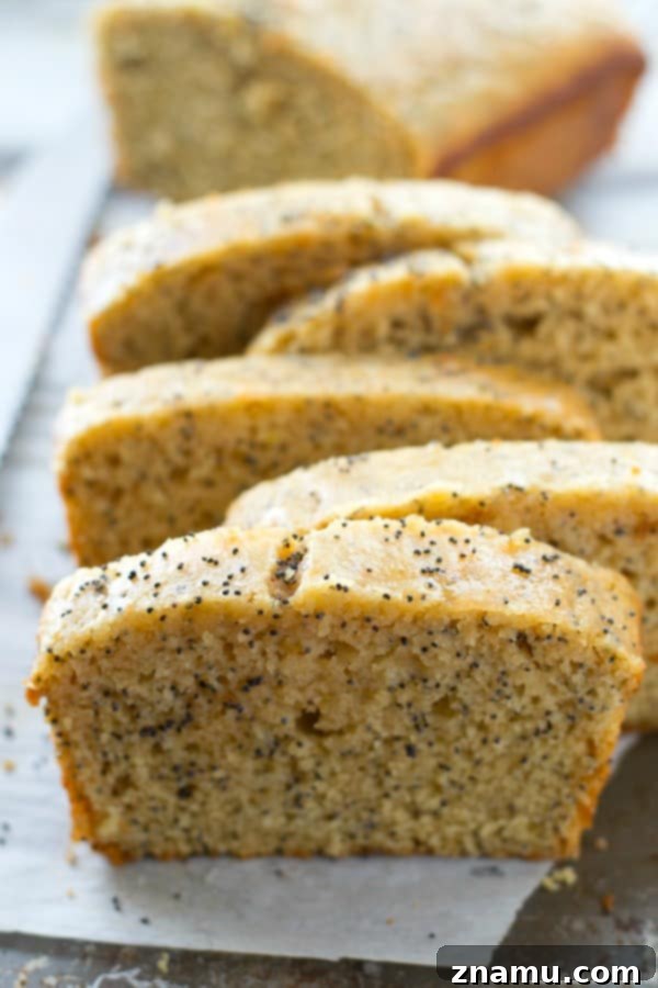 Zesty Poppy Drizzle Loaf 3 Close-up of a full loaf of Glazed Lemon Poppy Seed Bread, showcasing the generous lemon glaze dripping down the sides.