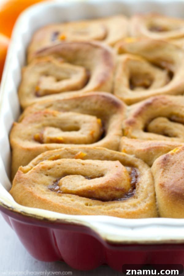 Thick Cream Cheese Icing on Orange Cinnamon Roll A side view of an orange cinnamon roll, highlighting the thick, creamy layer of homemade cream cheese icing.
