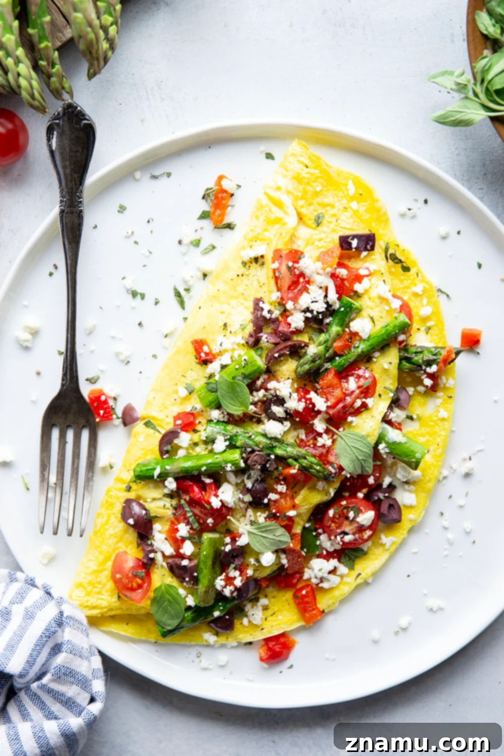 Mediterranean Asparagus & Feta Omelet 3 Close-up of a beautifully plated Greek omelet, showcasing the vibrant colors of cherry tomatoes, green asparagus spears, and white feta cheese against the golden eggs, promising a delicious and healthy meal.
