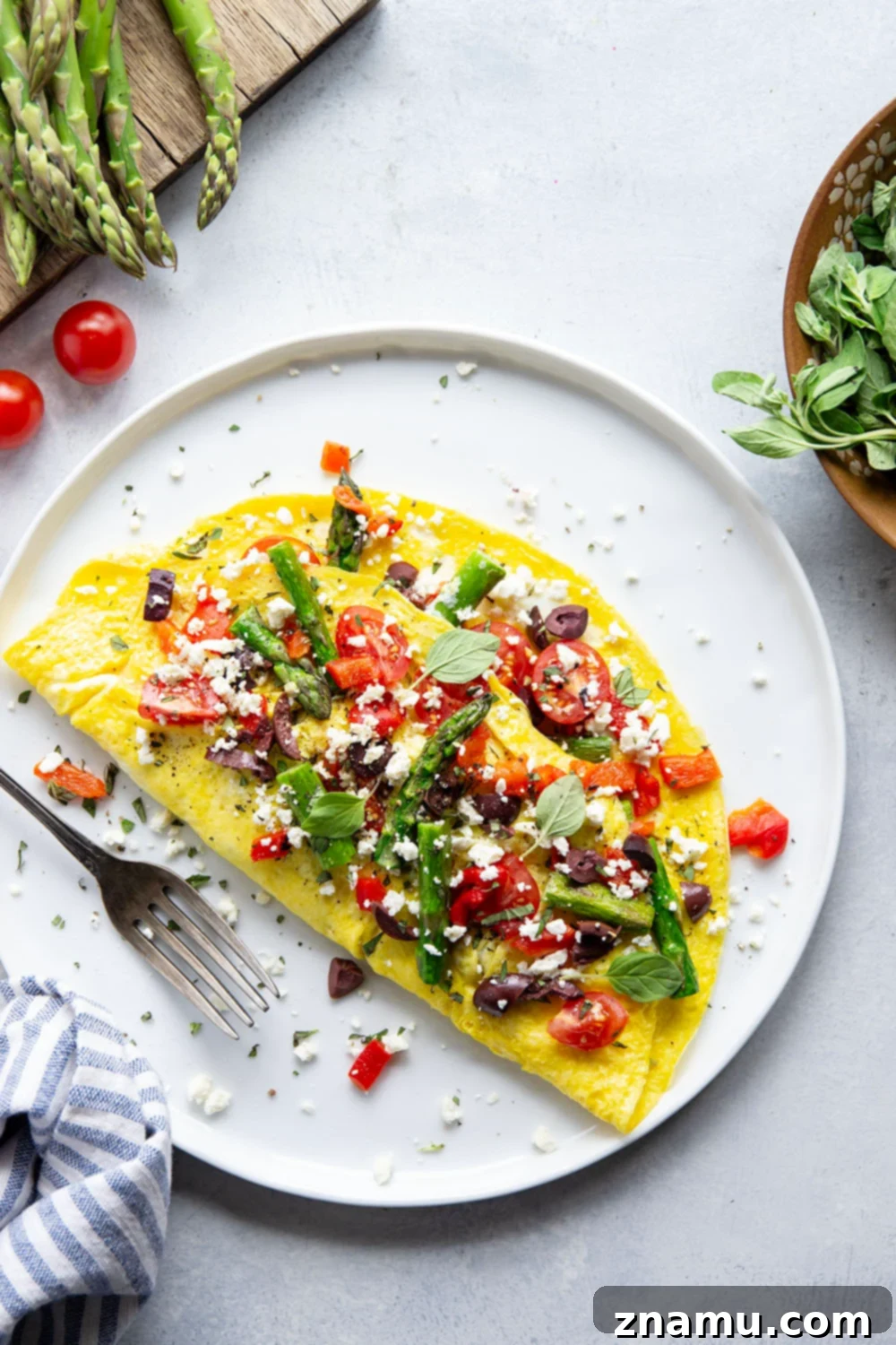 Mediterranean Asparagus & Feta Omelet 5 A close-up overhead shot of a perfectly cooked Greek omelet in a nonstick pan, filled with asparagus, tomatoes, and feta, demonstrating the ideal texture and presentation.