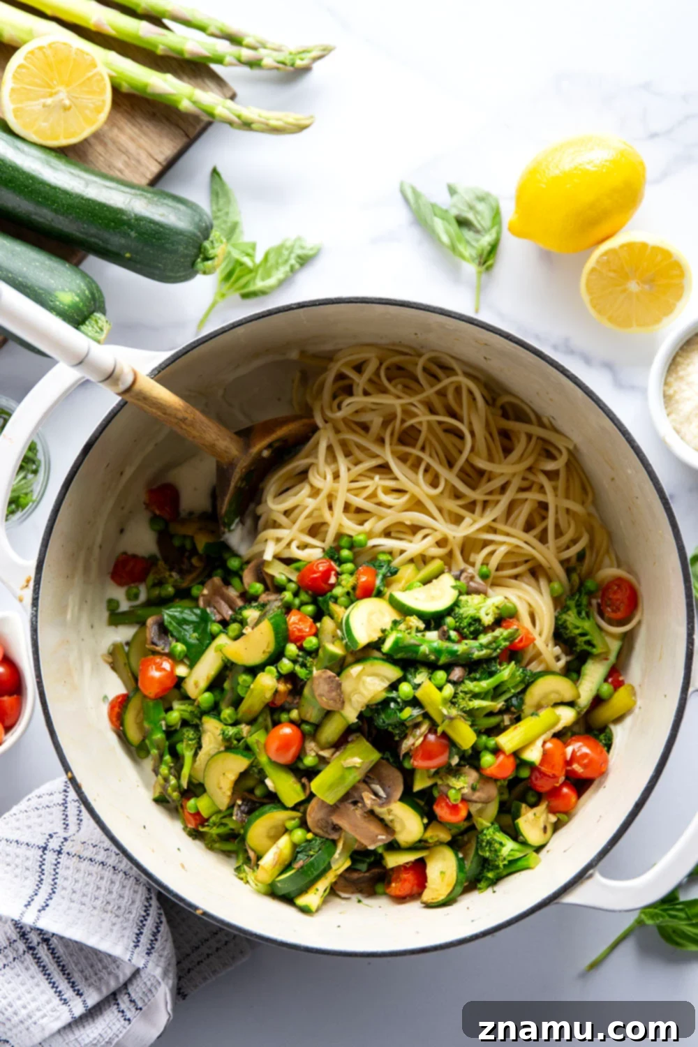 Vibrant Garden Pasta for Spring 3 Close-up shot of creamy fettuccine pasta intertwined with colorful vegetables like green asparagus, bright red cherry tomatoes, and vibrant green peas.