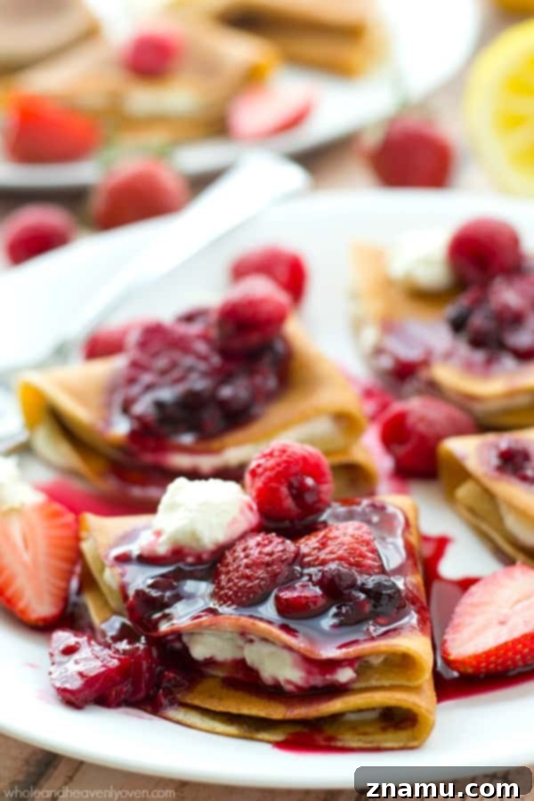 Filled with a tangy lemon cream cheese and topped with an unbelievable triple-berry sauce, these stunning crepes are a dream for any spring brunch!