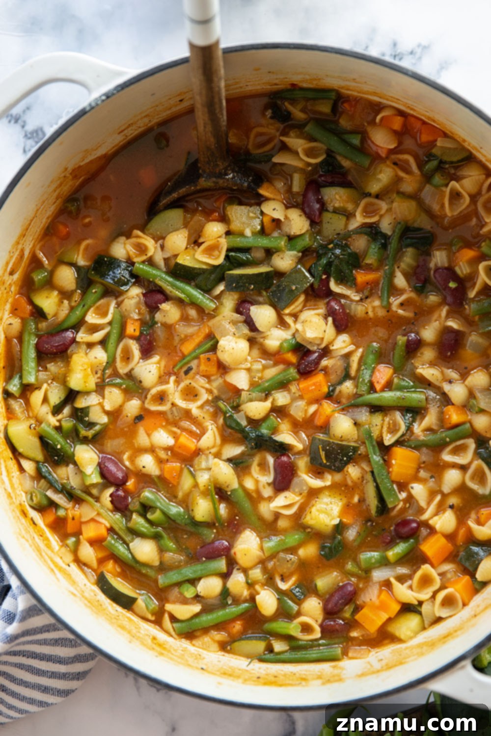 Hearty Vegetarian Minestrone 5 A bowl of minestrone soup served with crusty bread and a spoon, ready to be enjoyed.