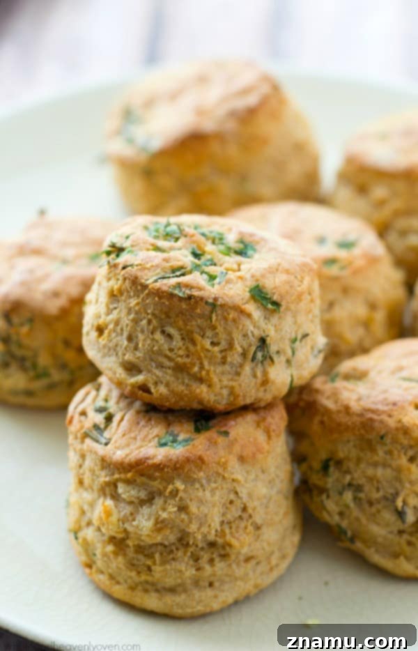 Close-up of baked Herbed Greek Yogurt Buttermilk Biscuits stacked on a wire rack, showcasing their fluffy texture.