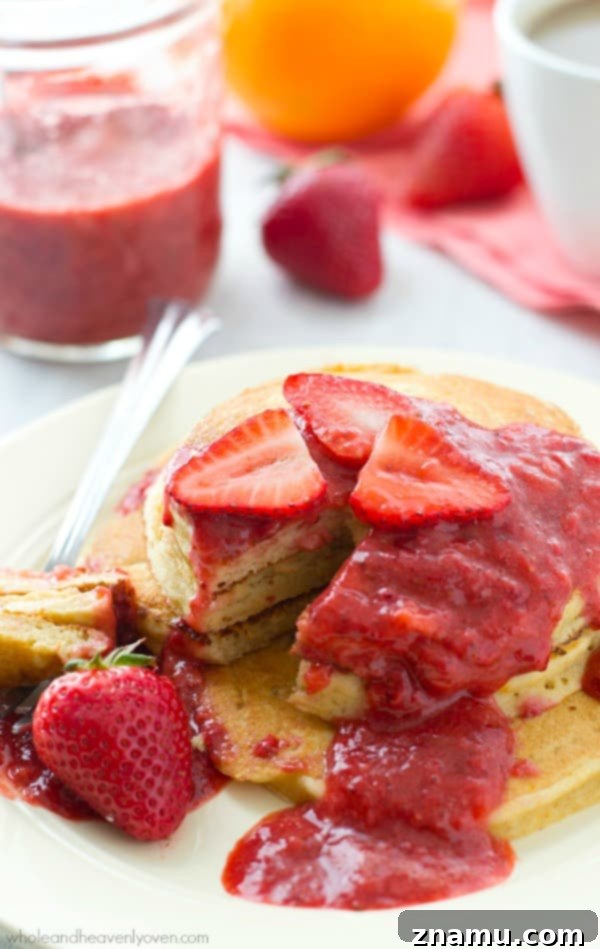 Zesty Orange Greek Yogurt Pancakes crowned with Roasted Strawberry Compote 8 A beautifully plated stack of orange Greek yogurt pancakes, garnished with fresh orange slices and generous roasted strawberry sauce, ready to be enjoyed.
