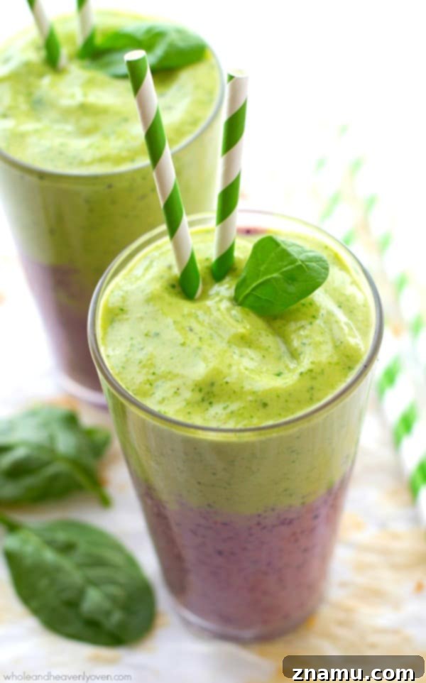 Vibrant Berry Green Energy Swirl 8 Final shot of a hand holding a layered mixed berry and green power smoothie against a light background