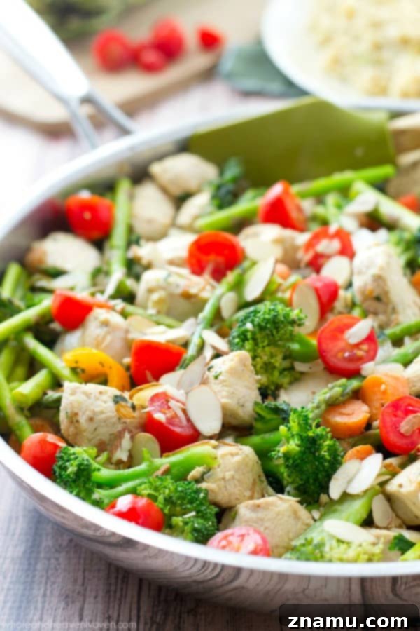 Chicken Asparagus Stir-Fry with Sweet Tomatoes and Crunchy Almonds 3 A close-up of a colorful chicken and vegetable stir-fry, showcasing fresh ingredients like asparagus, carrots, and bell peppers.