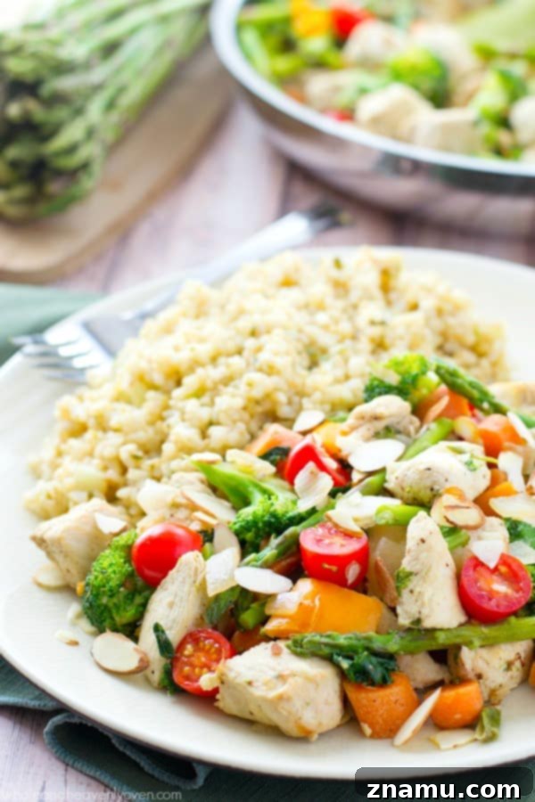 Chicken Asparagus Stir-Fry with Sweet Tomatoes and Crunchy Almonds 5 Chicken and various chopped vegetables cooking in a large skillet, releasing fragrant steam.
