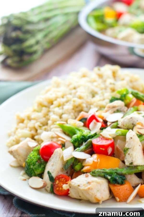 Chicken Asparagus Stir-Fry with Sweet Tomatoes and Crunchy Almonds 7 A bowl of fresh chicken and asparagus stir-fry, topped with crunchy toasted almonds and ready to be enjoyed.