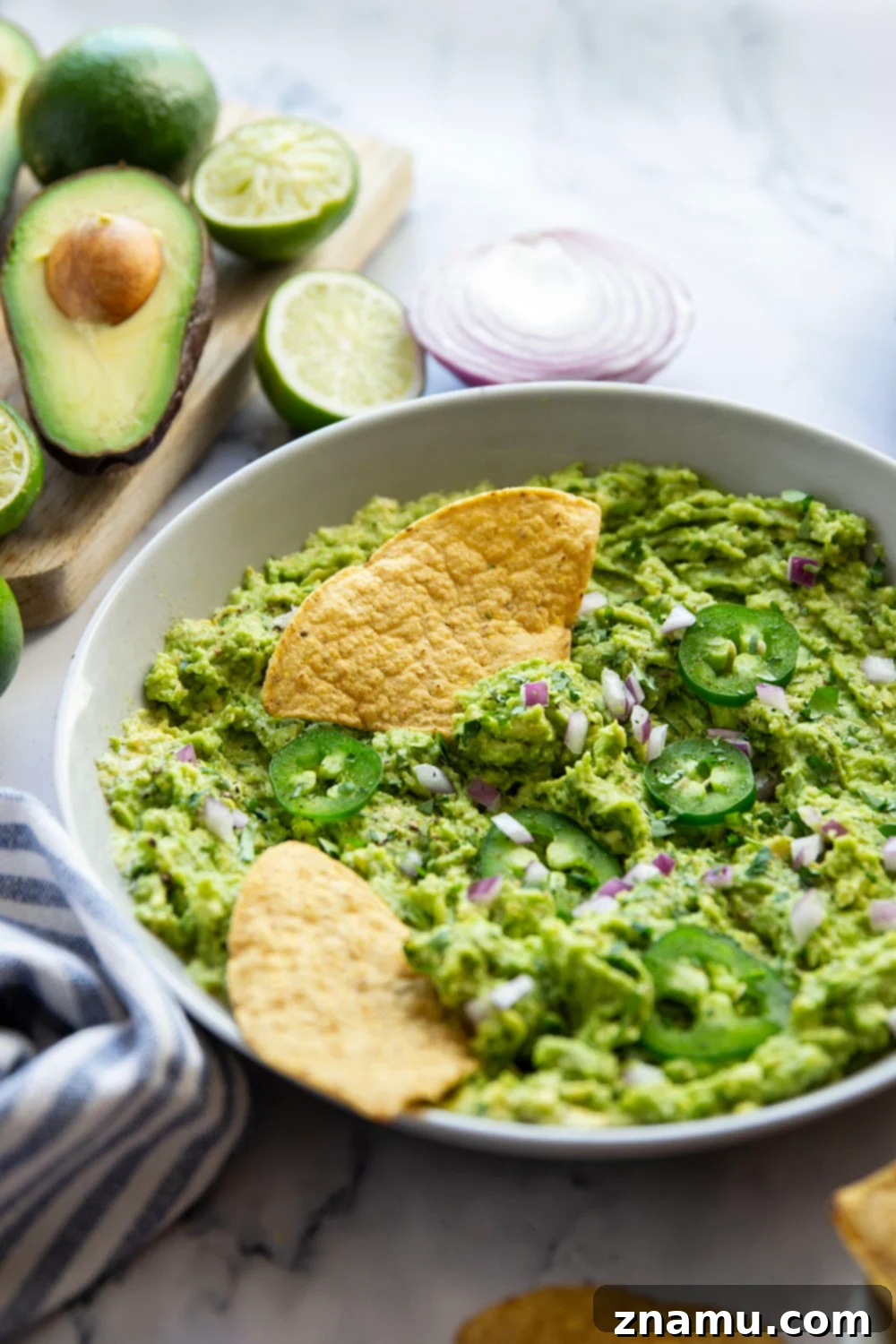 The Ultimate Guacamole Recipe 6 A large bowl of fresh guacamole, garnished with cilantro and lime, surrounded by tortilla chips.