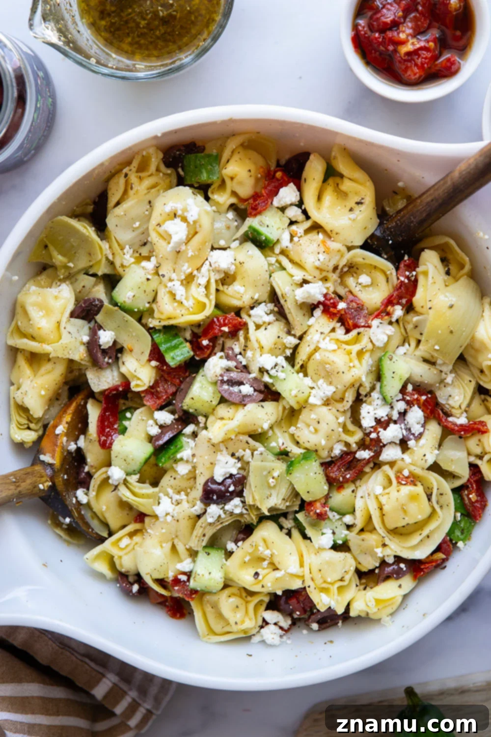 Vibrant Mediterranean Tortellini Pasta Salad 4 Ingredients for Mediterranean tortellini pasta salad laid out on a table.