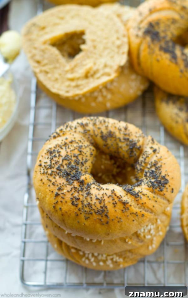 Authentic Homemade Deli Bagels 5 A stack of golden-brown homemade bagels with various toppings sits on a light-colored surface, ready to be enjoyed.