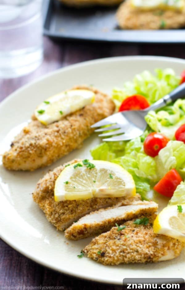 Irresistible Lemon-Garlic Crusted Chicken Tenders 2 Golden-brown, crispy lemon-garlic breaded chicken tenders fresh from the oven, garnished with parsley.