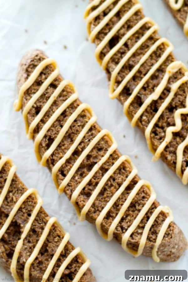 Hand holding a piece of chocolate biscotti, perfectly crisp and coated in luxurious peanut butter glaze, ideal for dipping.