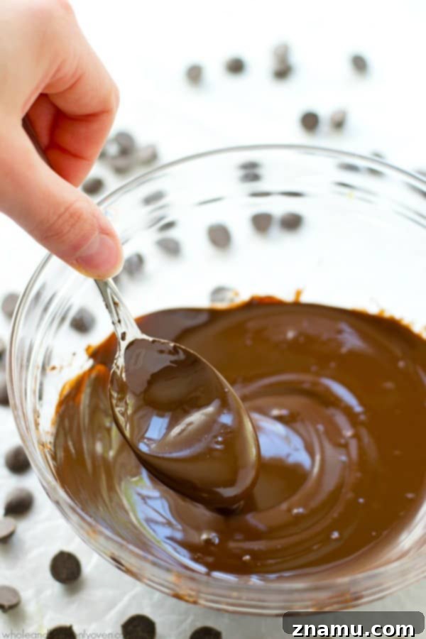 Mastering the Art of Chocolate Melting 8 A spoon emerging from a bowl of glossy melted chocolate, perfect for a taste test.