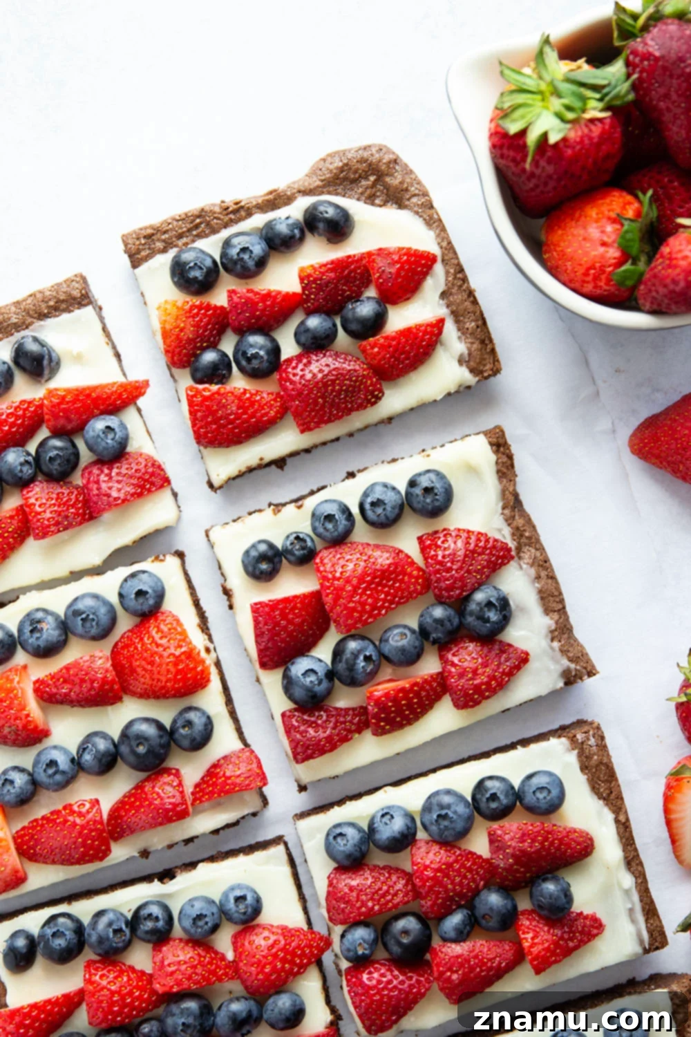 Red, White & Blue Brownie Pizza 3 Close-up of the 4th of July brownie dessert pizza, highlighting the thick layer of cream cheese frosting and the glistening fresh berries. The brownie base peeks out from beneath the frosting.