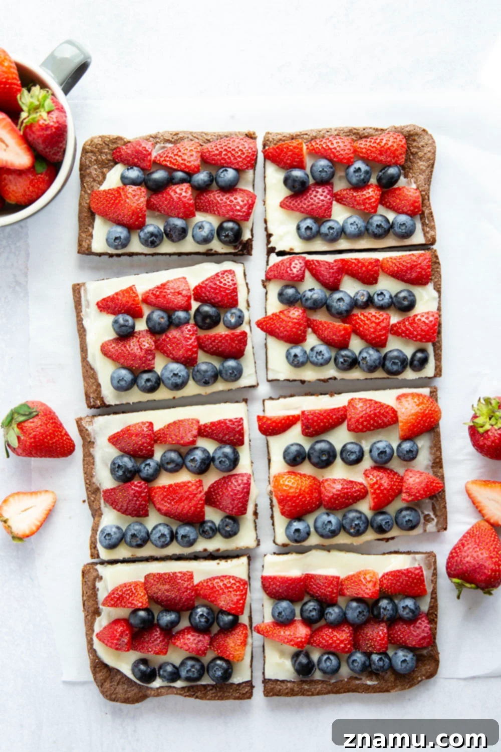 Red, White & Blue Brownie Pizza 6 Another appealing shot of the 4th of July brownie dessert pizza, presented on a cutting board, with various pieces already cut and ready to serve.