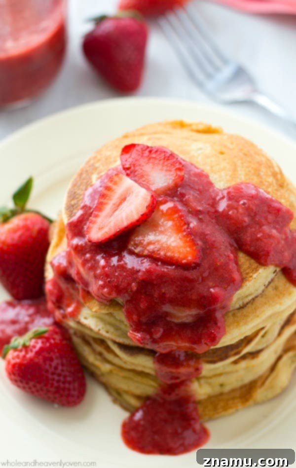 Colossal Buttermilk Blueberry Pancake 11 Fluffy orange Greek yogurt pancakes served with a vibrant roasted strawberry sauce, perfect for a refreshing breakfast.