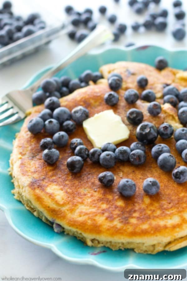 Colossal Buttermilk Blueberry Pancake 3 Close-up shot of an XXL blueberry buttermilk pancake showing its fluffy texture and generous amount of blueberries.
