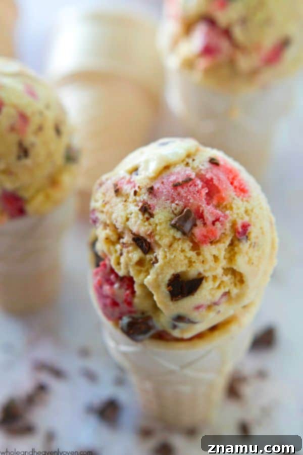Crimson Chip Swirl Bliss 4 A scoop of Strawberry Swirl Chocolate Chip Ice Cream in a waffle cone, ready to be enjoyed.