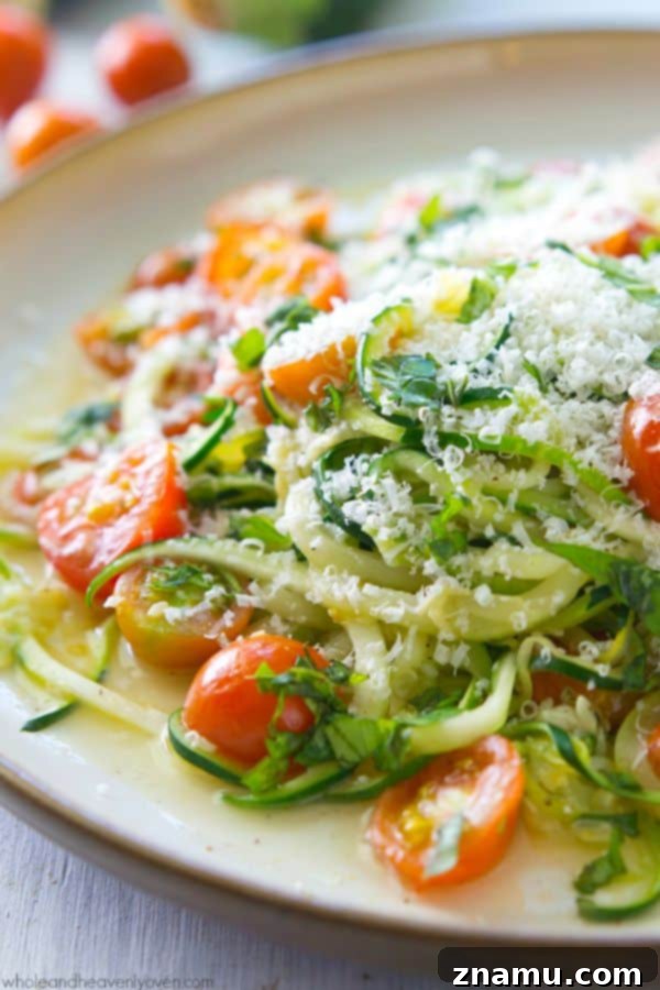 Light Parmesan Zoodles with Sweet Cherry Tomatoes 7 A close-up view of zucchini noodles, cherry tomatoes, and garlic gently sautéing in olive oil in a pan.