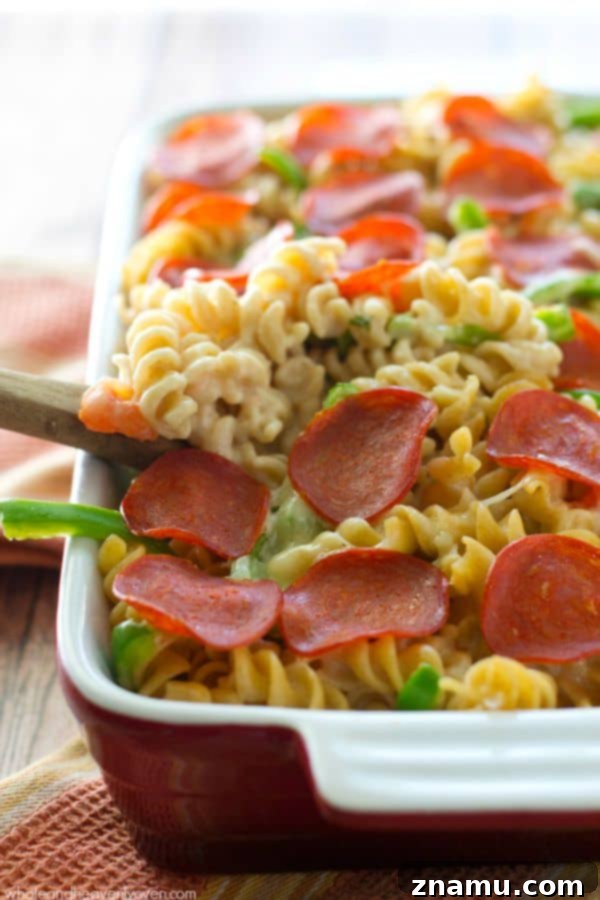 Ultimate Pepperoni Pizza Macaroni and Cheese 4 Pepperoni slices arranged on a bed of cheesy pasta before baking, illustrating the one-pan cooking method.
