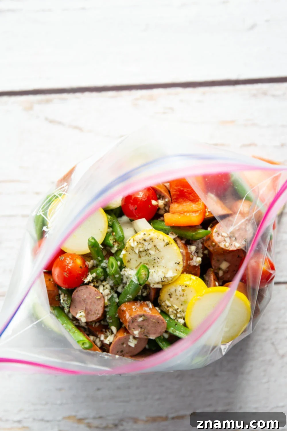 Zesty Marinated Grilled Summer Vegetables and Sausage 5 Sliced chicken sausage and various vegetables on a grill pan, ready for grilling.