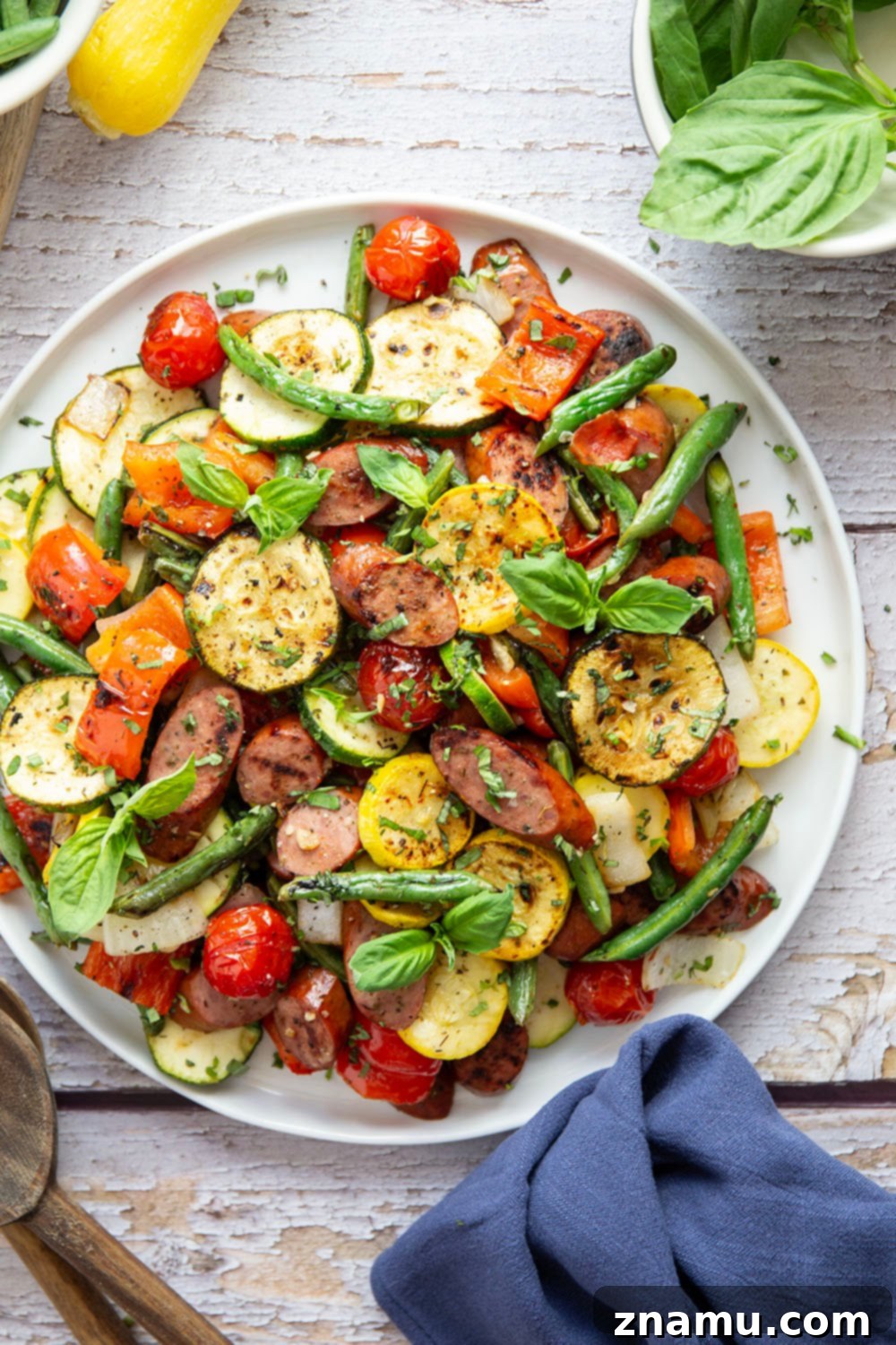 Zesty Marinated Grilled Summer Vegetables and Sausage 6 Close-up of a plate filled with Marinated Grilled Summer Vegetables and Sausage, garnished with fresh basil.