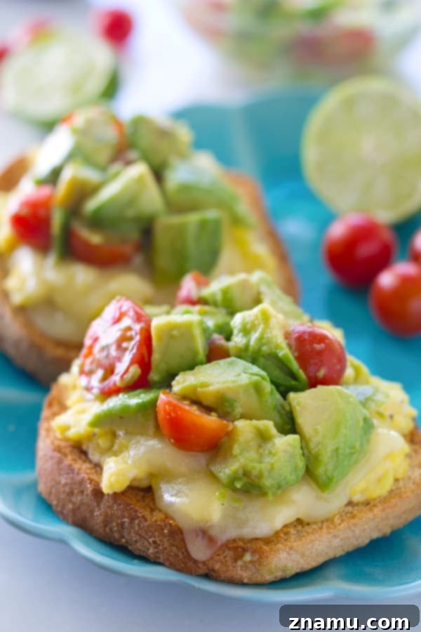 Cheesy Scramble Toast with Fresh Avocado and Burst Tomatoes 2 Crispy toast topped with fluffy scrambled eggs, melted mozzarella cheese, and a fresh avocado cherry tomato salad, ready for an easy gourmet breakfast.