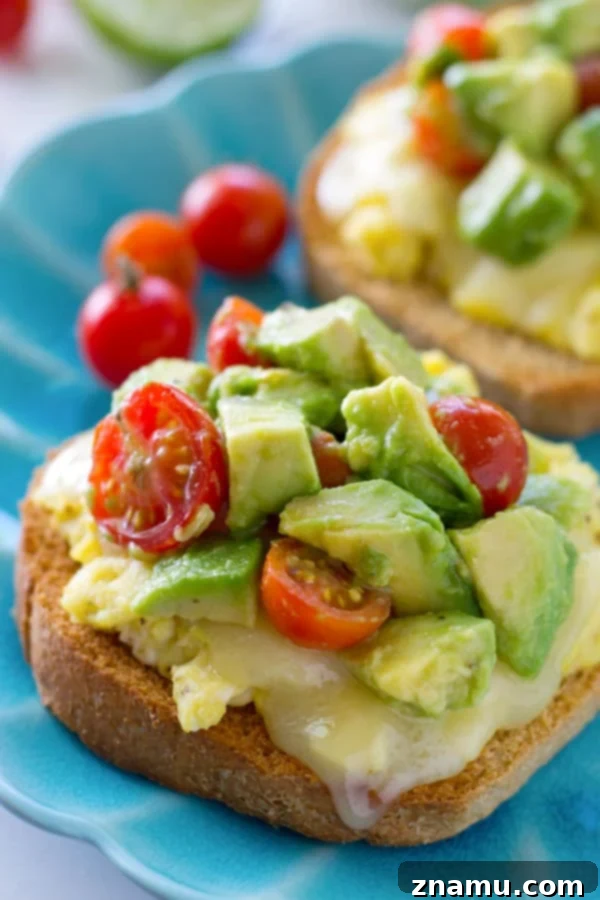 Cheesy Scramble Toast with Fresh Avocado and Burst Tomatoes 4 A hand holding a beautifully prepared scrambled egg toast, highlighting its portability and deliciousness.