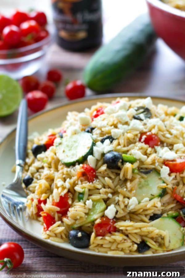 A beautifully presented bowl of Greek Orzo Pasta Salad, highlighting colorful cherry tomatoes and fresh herbs, perfect for a summer gathering.