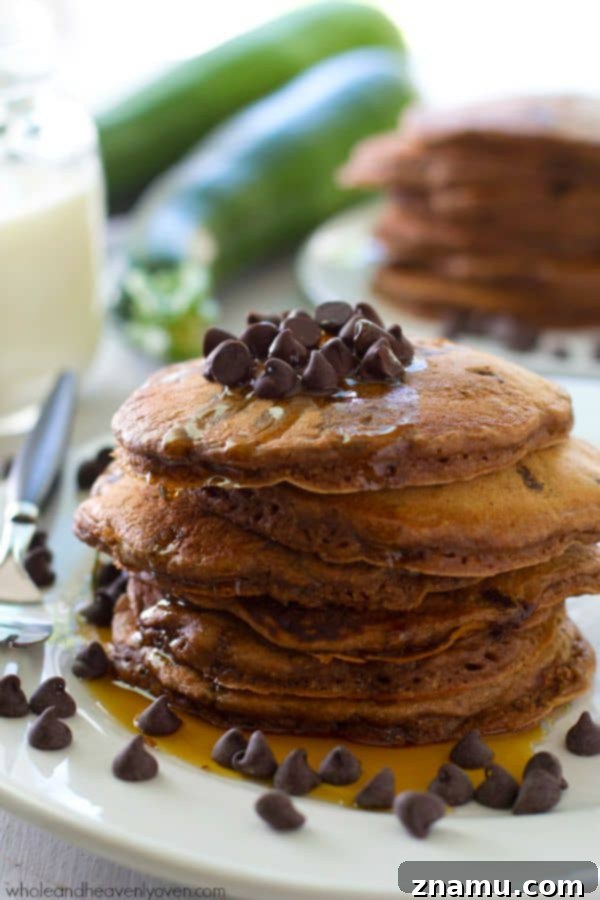 Decadent Double Chocolate Zucchini Pancakes 3 A stack of perfectly cooked Double Chocolate Zucchini Pancakes, featuring a rich brown hue from cocoa and melted chocolate chips, hinting at the delightful flavors within. @WholeHeavenly