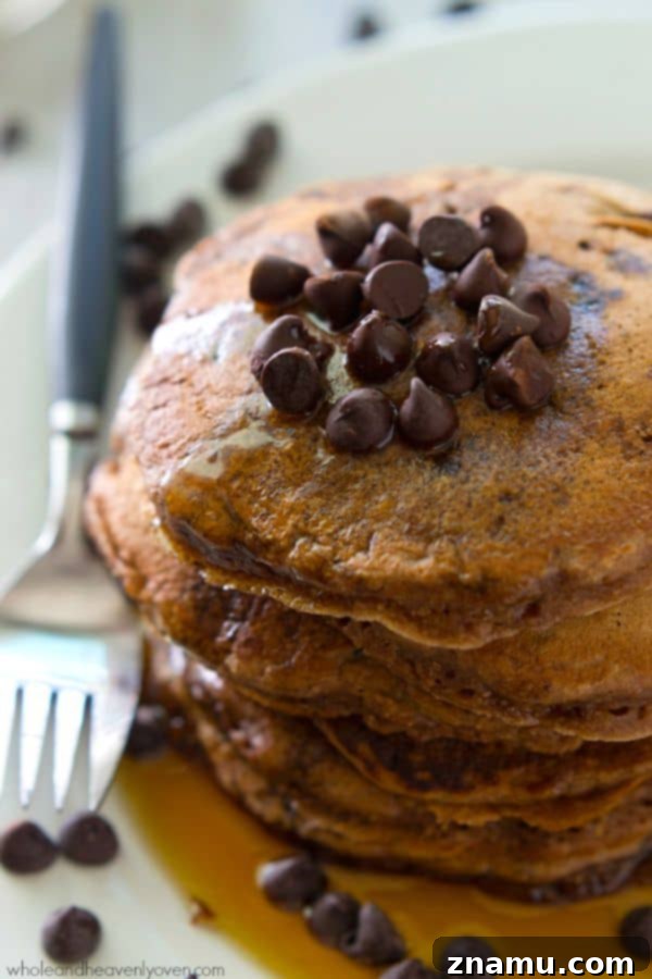 Decadent Double Chocolate Zucchini Pancakes 4 Close-up of a plate of fluffy Double Chocolate Zucchini Pancakes, generously drizzled with maple syrup, highlighting their moist texture and irresistible appeal. @WholeHeavenly