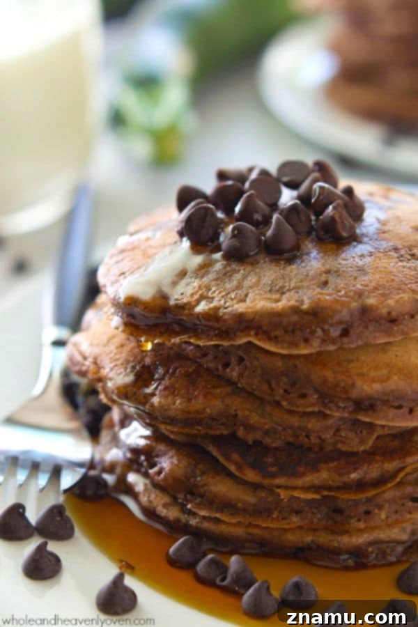 Decadent Double Chocolate Zucchini Pancakes 5 A serving of Double Chocolate Zucchini Pancakes with a clear view of their inviting texture, ready for a generous topping of maple syrup. @WholeHeavenly
